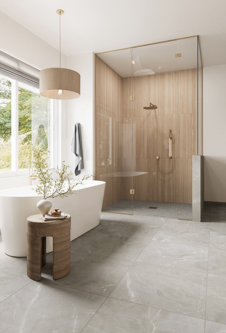 A modern bathroom featuring a freestanding bathtub, a wooden stool with a vase, and a walk-in shower with wood-look tile walls and a glass enclosure.