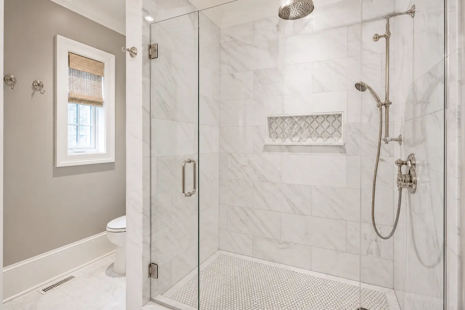Classic marble walk-in shower with glass door, mosaic floor and nickel fixtures